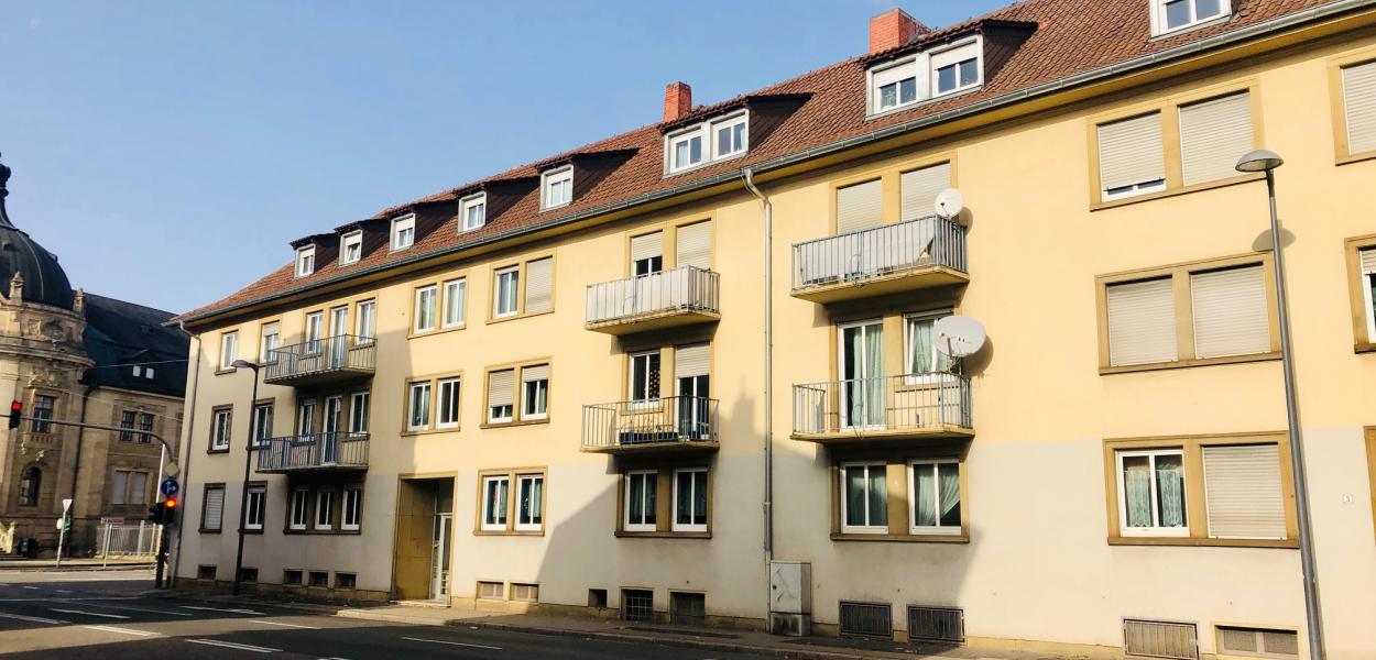 Gelbes Haus mit mehreren Wohnungen an Kreuzung