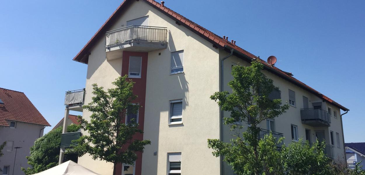 Modernes Haus mit Wohnungen, Balkon und Grünanlage