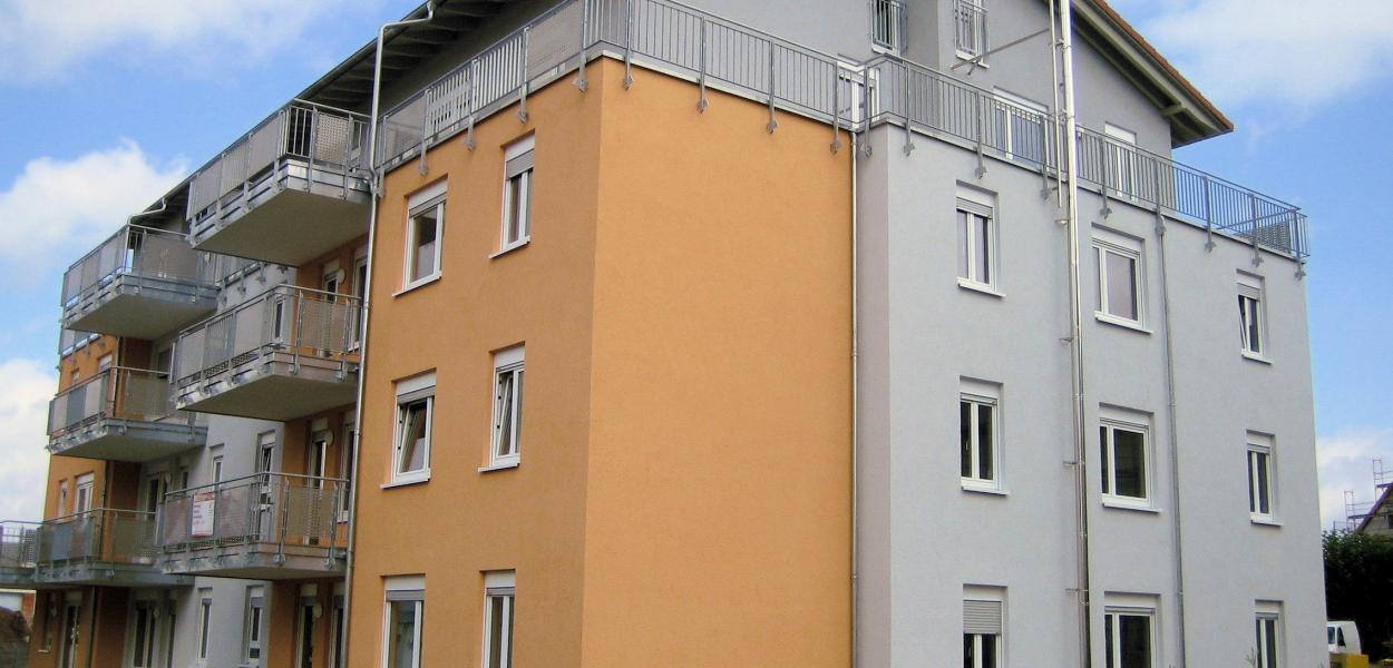 Haus mit orangener und grauer Fassade und vielen Wohnungen